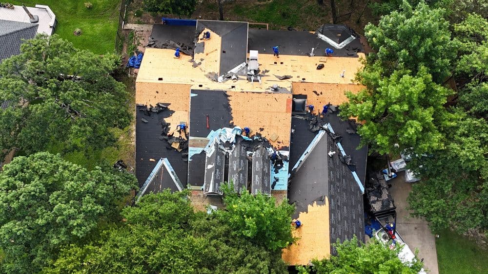 Roof replacement in progress on a residential home with workers and new materials visible.