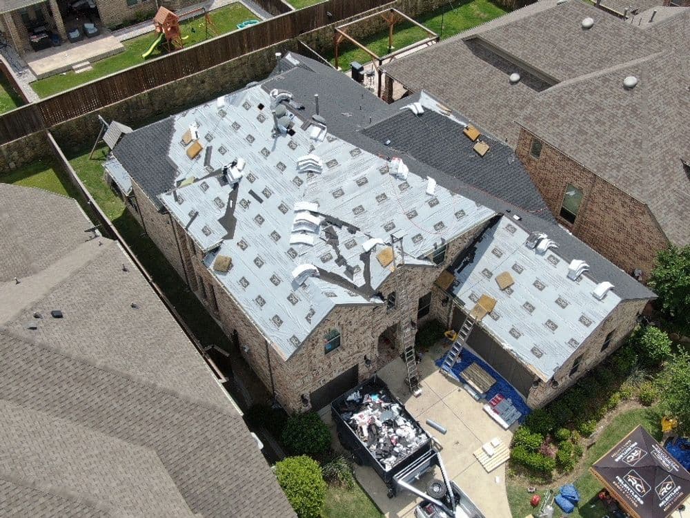 Aerial view of a house roof under renovation with materials and tools visible.