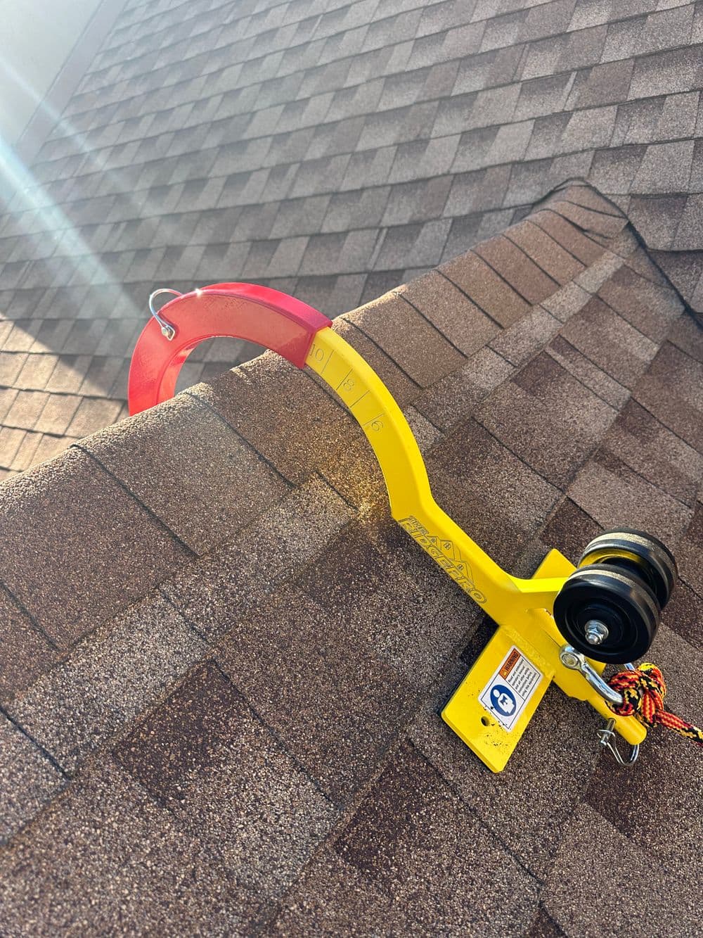 Roof safety harness anchor system installed on a shingled rooftop for fall protection.