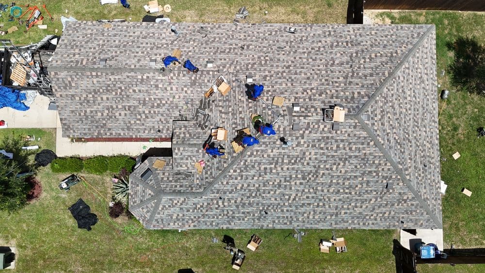 Workers installing a new roof on a residential home using shingles.