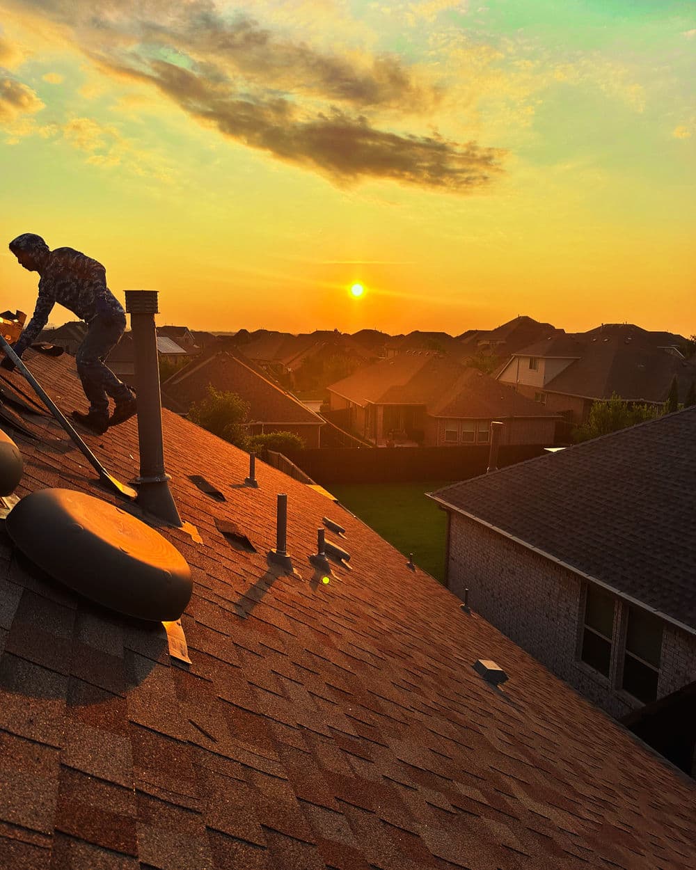 Roof repair at sunset with a technician working on a residential home rooftop.