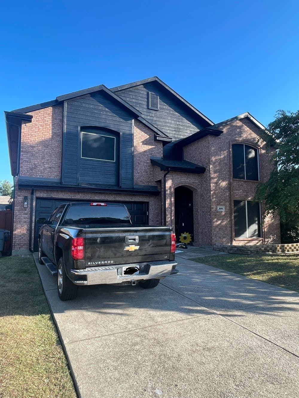 Modern brick house with black accents and a driveway featuring a parked black pickup truck.