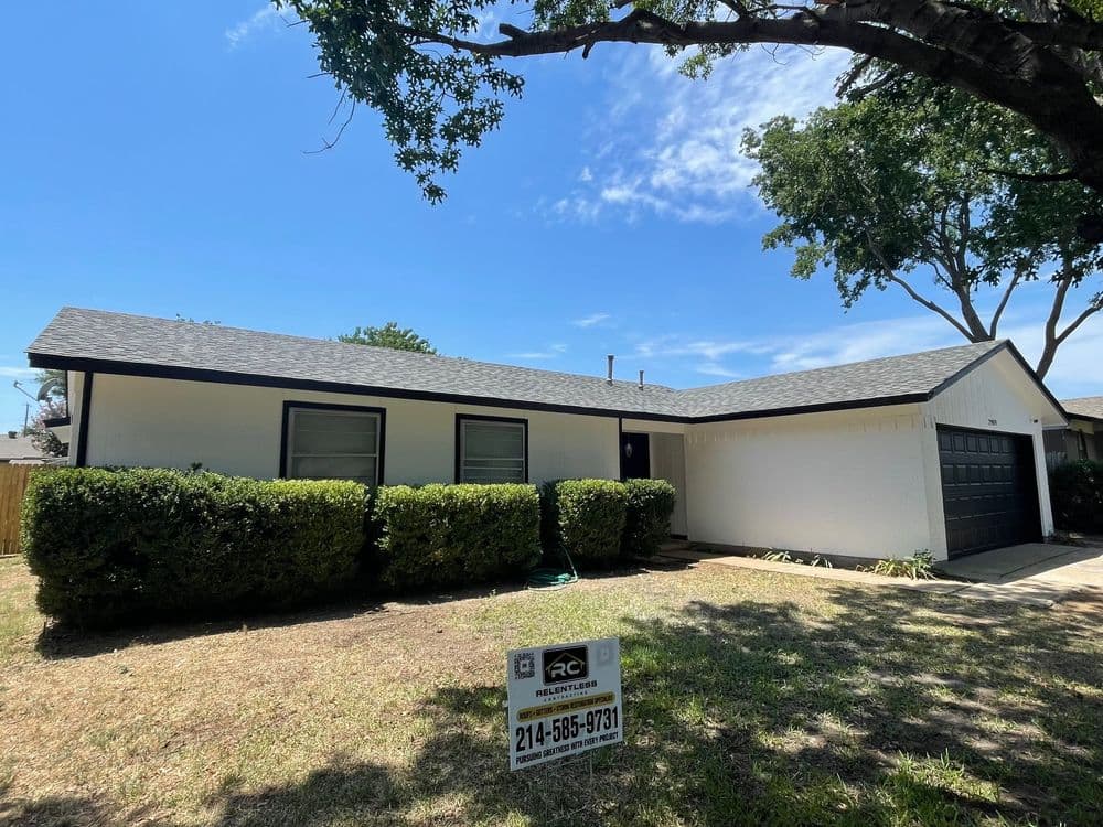 Single-story white house with black trim, garage, and well-maintained yard for sale.