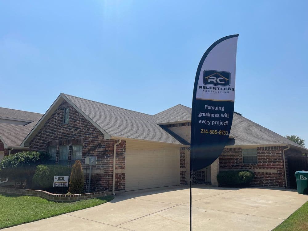 Residential home with "Relentless Contractors" sign promoting services on a sunny day.