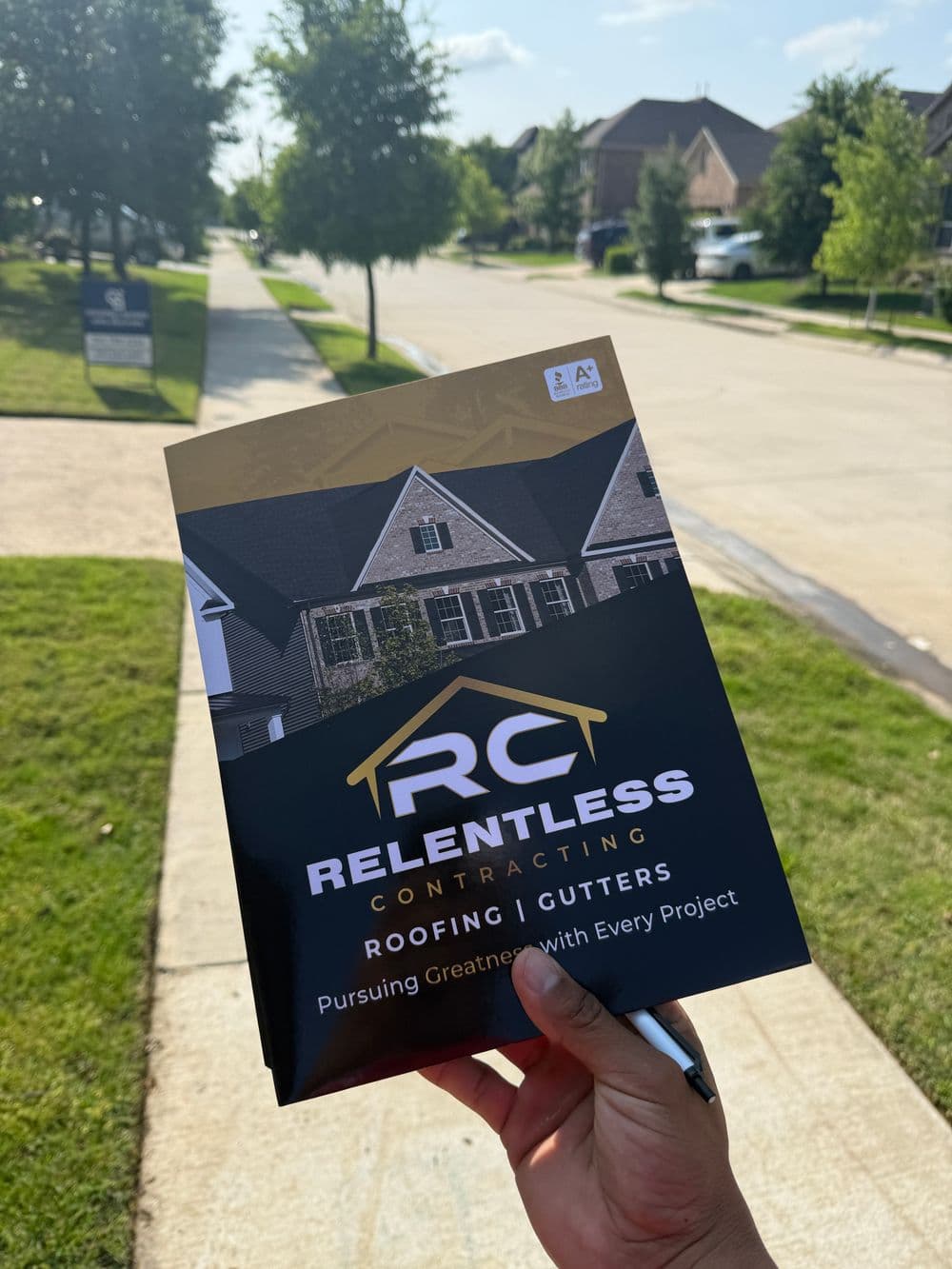 Hand holding a brochure for RC Relentless Contracting featuring roofing and gutter services.