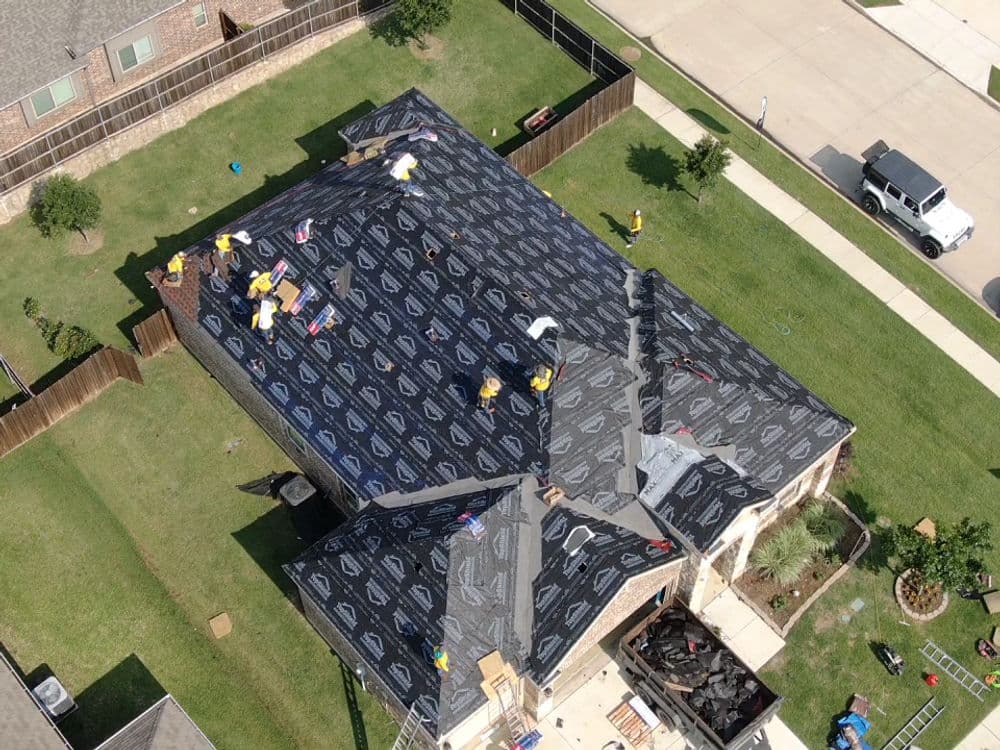 Roof installation in progress on a residential home, crew working with roofing materials.