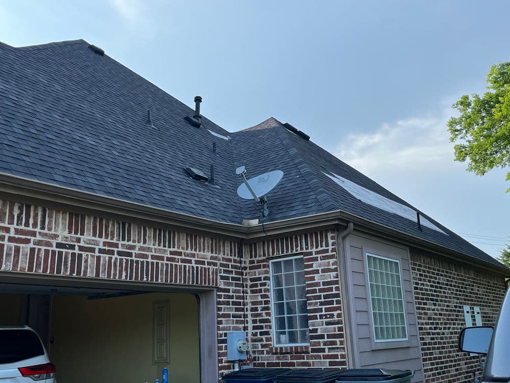 Satellite dish mounted on a sloped roof of a brick garage with clear sky in the background.