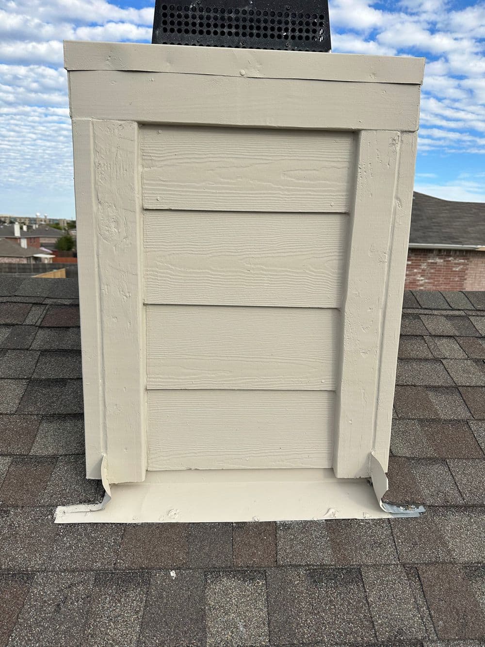 Roof ventilation system with wooden paneling on shingled rooftop under cloudy sky.