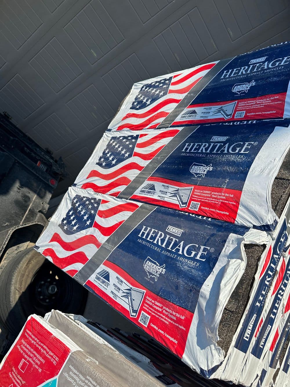 Heritage roofing shingles displayed with American flag design in a garage setting.