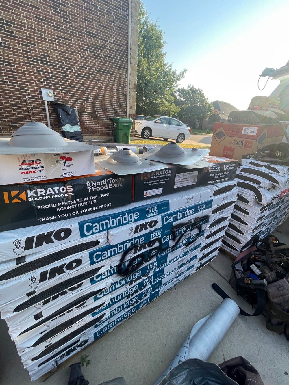 Roofing materials stacked outside a building, featuring IKO and Cambridge brand products.