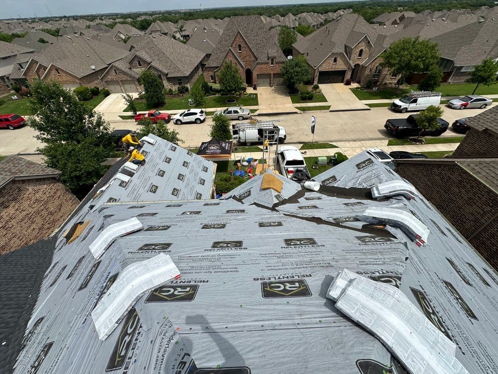 Aerial view of homes with a roof under renovation, showcasing roofing materials and equipment.