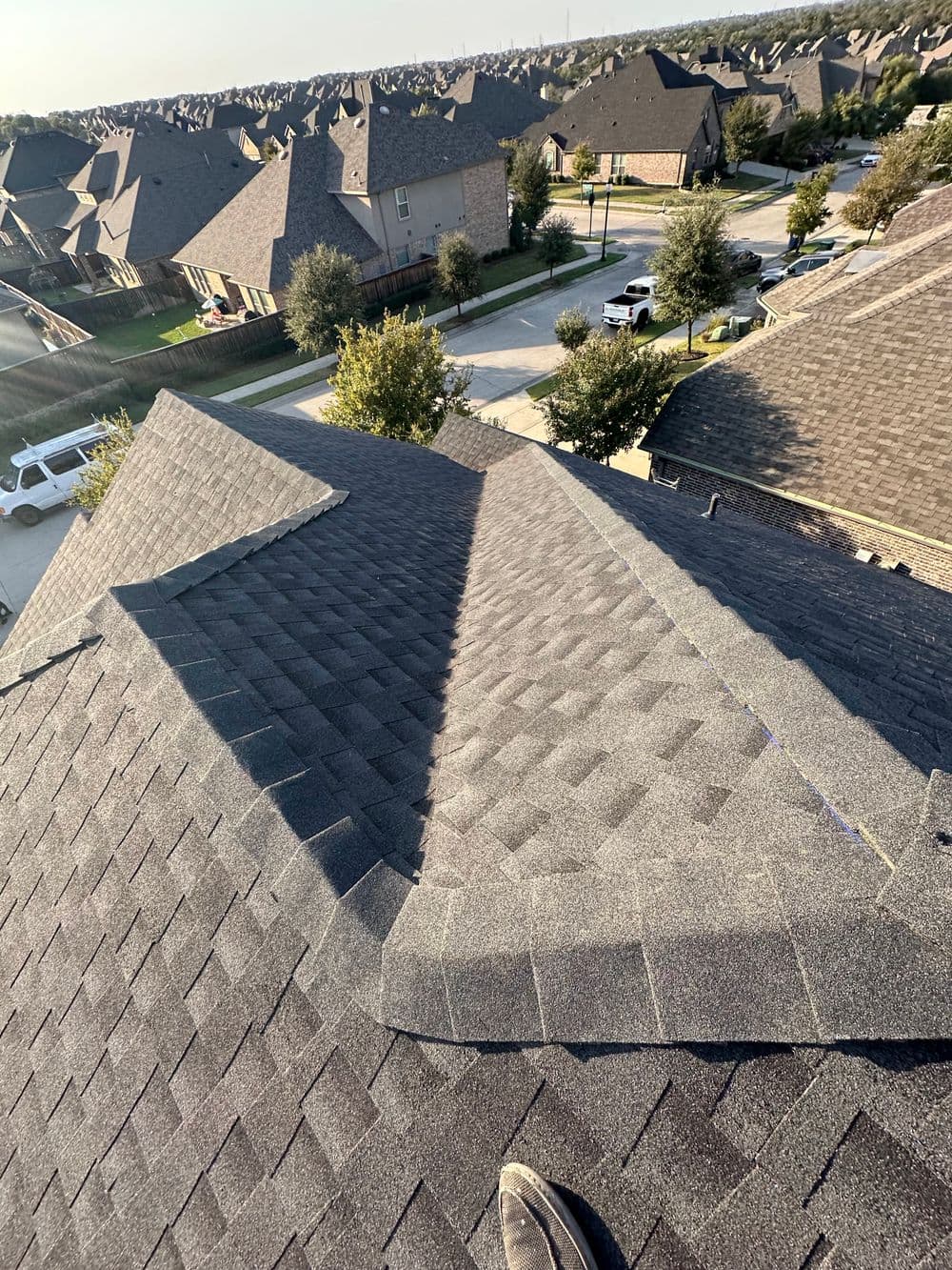 Roofing inspection view showing asphalt shingles on a residential neighborhood.