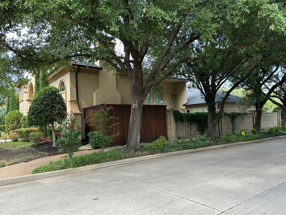 Elegant two-story home surrounded by lush trees and vibrant landscaping along a peaceful street.