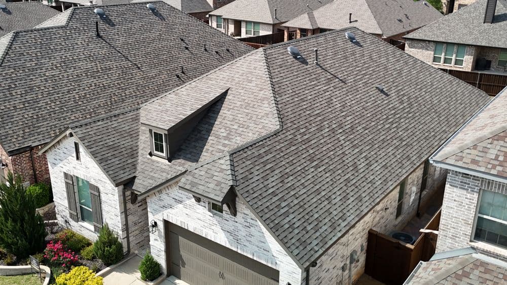 Aerial view of a suburban home with a modern roof, surrounded by well-maintained lawns.