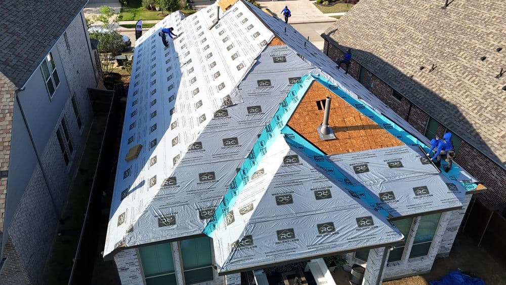 Roofers installing a new roof on a residential home with visible underlayment and tools.